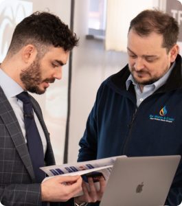 Two men in suits focused on a laptop screen, engaged in a professional discussion.